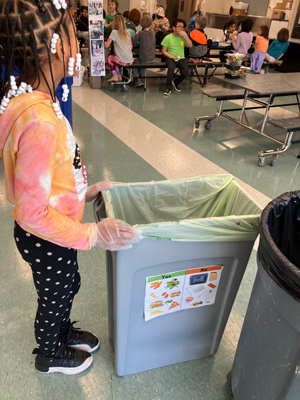 Small child stood next to a food waste bucket