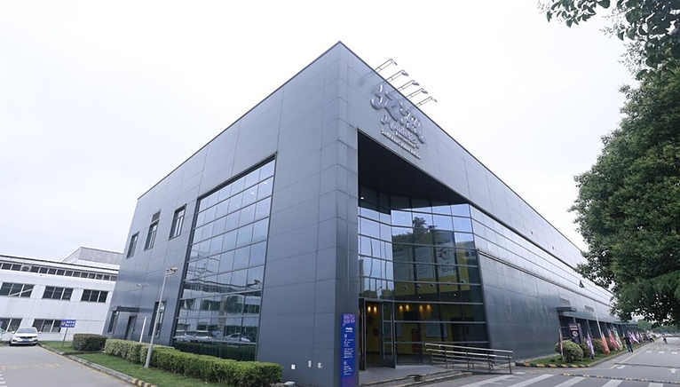 Exterior of an office building. A sign in a foreign language above the high front opening.