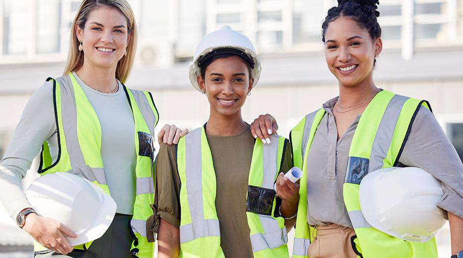 Women in construction. Three women shown wearing hardhats and construction vests.