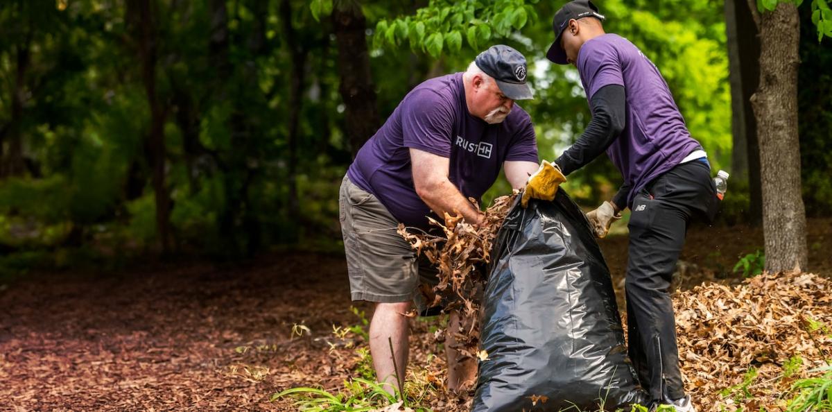 Two Truist volunteers stuffing debris into a bag.