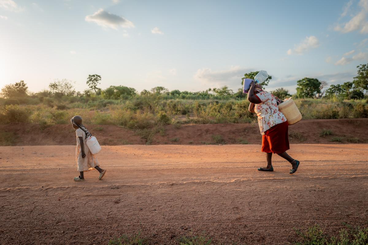 Celestine and her grandmother carrying water