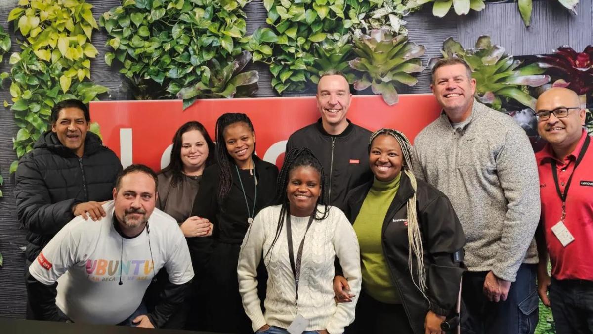 Werner Schoeman and team members in front of a Lenovo sign.