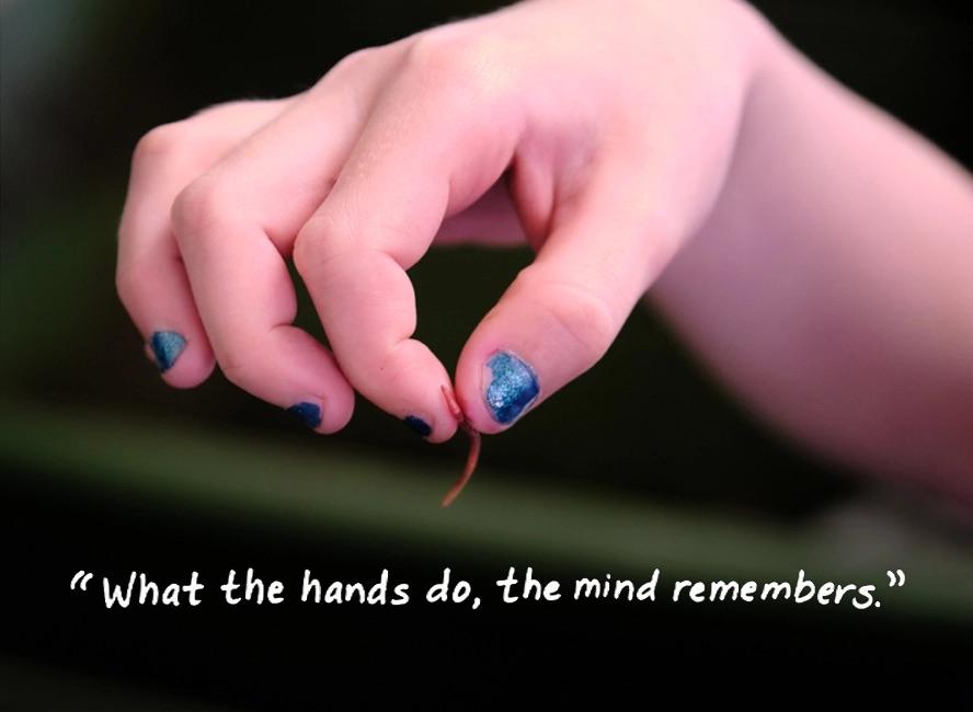 "what the hands do, the mind remembers." with a hand holding a tiny worm