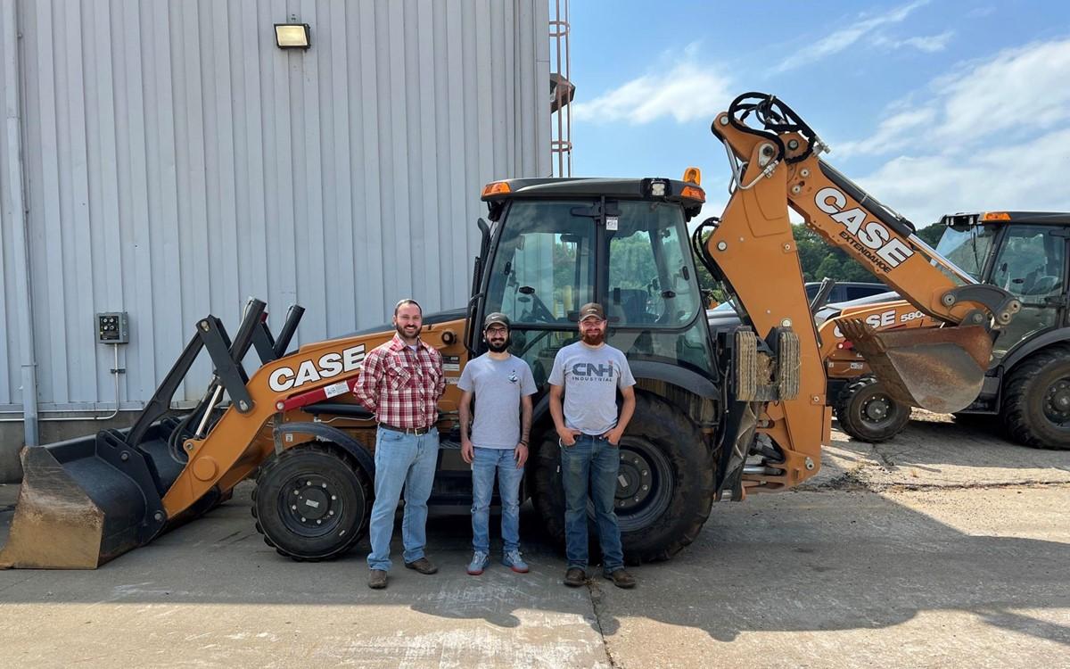 Three people standing in front of a large Case combo-loader