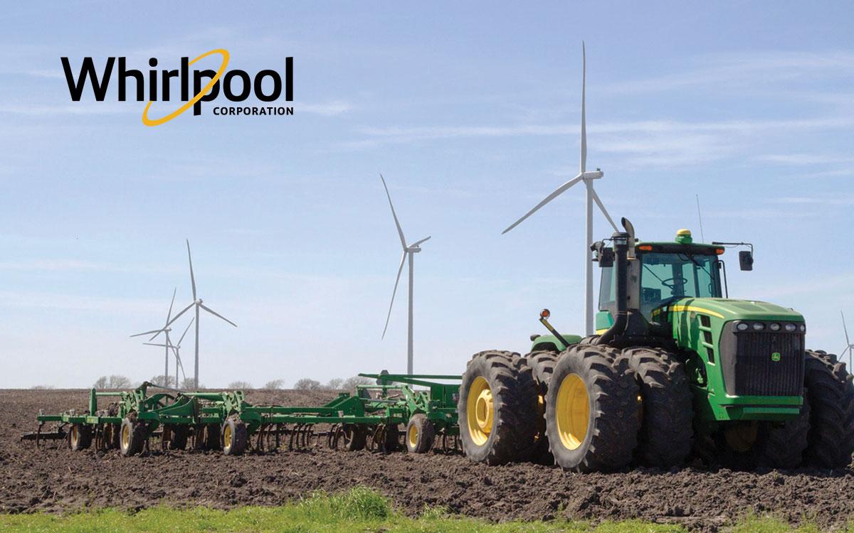 A large green tractor tills a field, wind turbines behind it in a row. Whirlpool logo in the upper left.