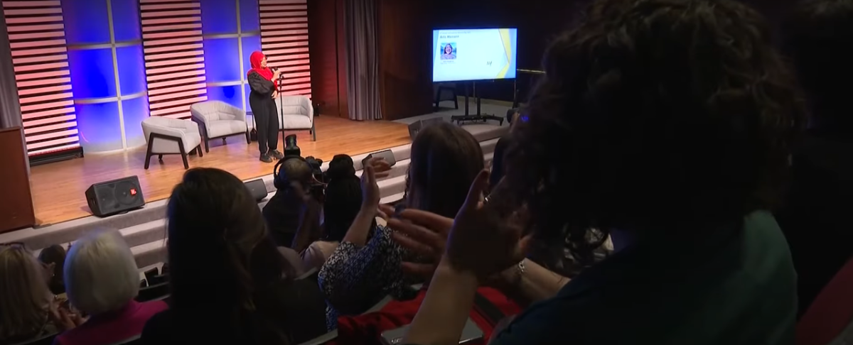 Image courtesy of 11Alive Saleemah Abdul-Ghafur speaking on a stage with three armchairs. An audience in front of her.
