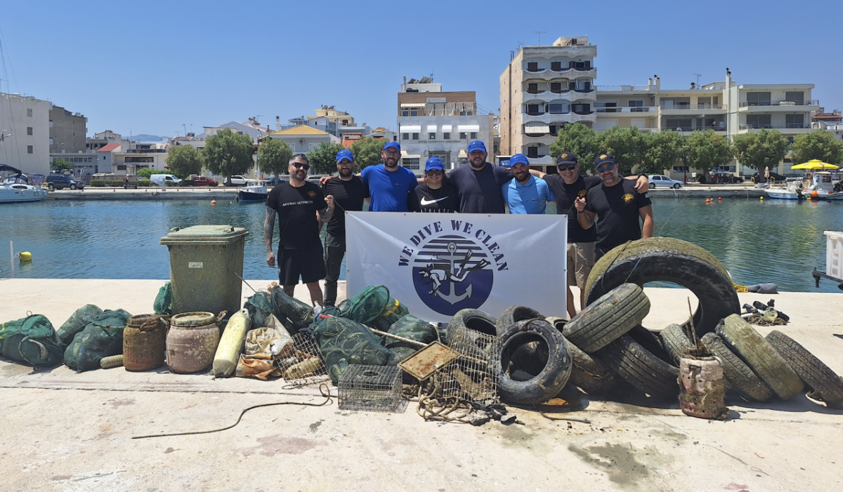 Group photo of volunteers next to the large pile of garbage they removed from the water