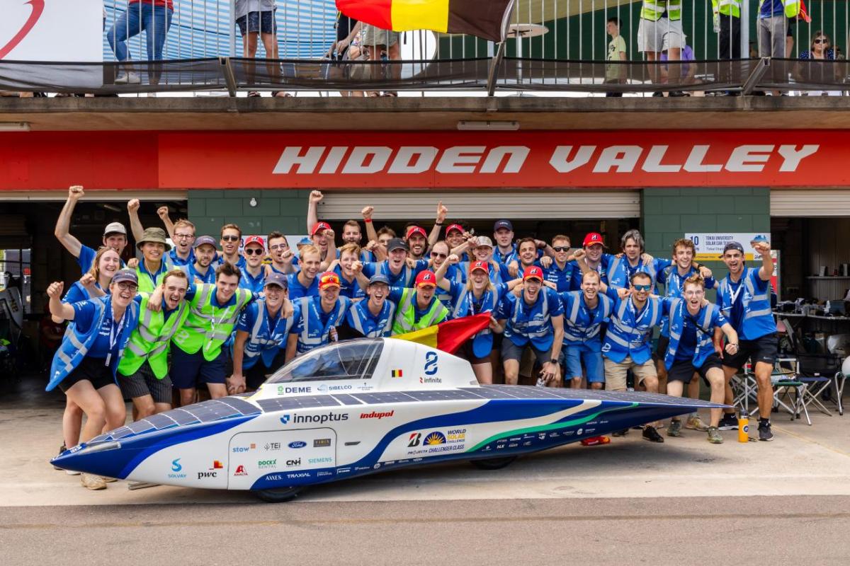 Team Innoptus stood behind a solar car 