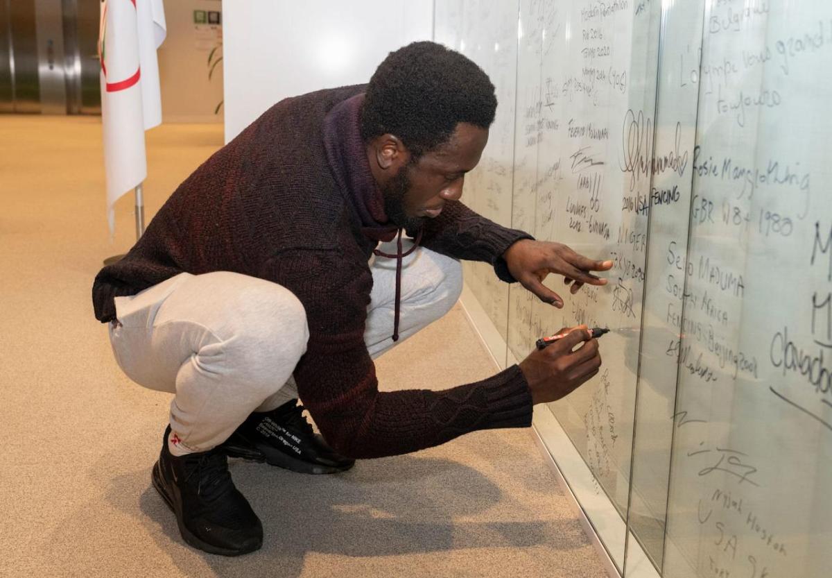 A person knelt down writing on a white board