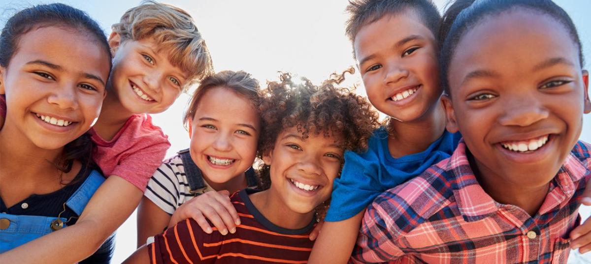 A group of children leaning on each other, smiling  