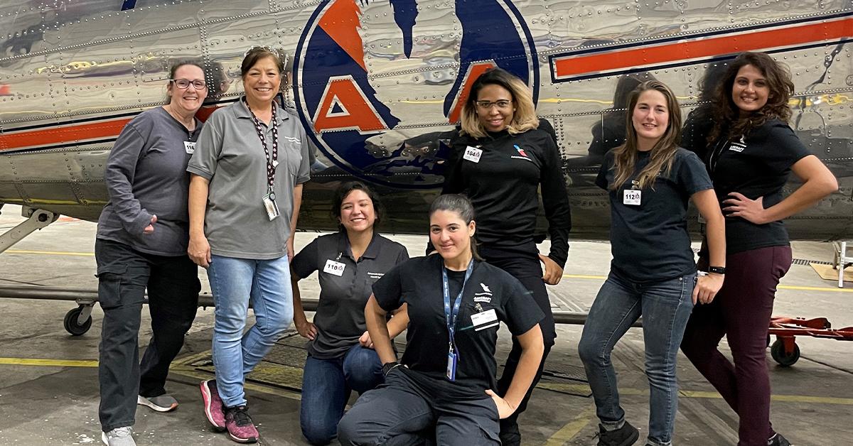 The Women in Tech Ops team accompanied by a student from Tarrant County College during their practice session this month at the Tulsa Base Maintenance facility. 7 women standing with a plane