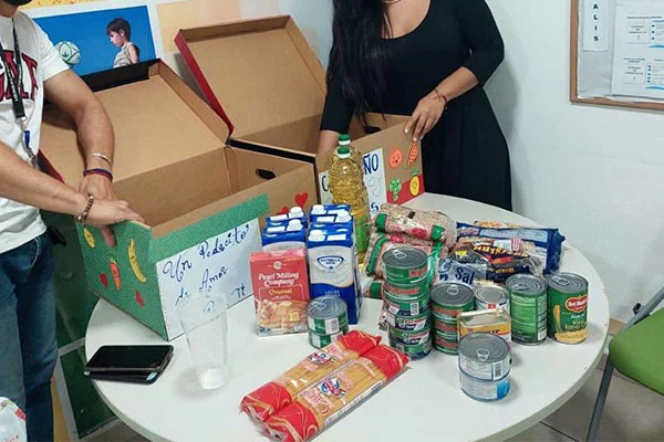 In a home kitchen, two people pack boxes with food