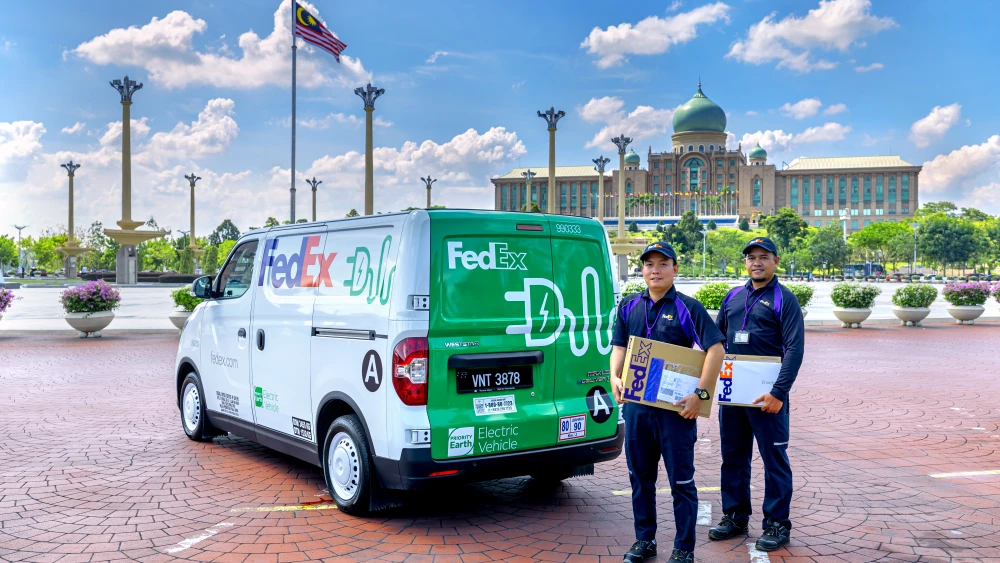 FedEx employees holding packages, next to vehicles
