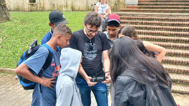 Students in a circle around an adult, looking at something