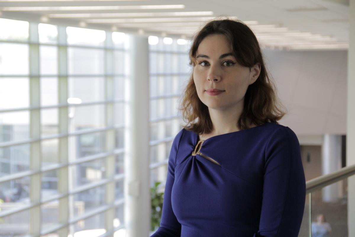 A person in an office building, a large wall of windows behind them