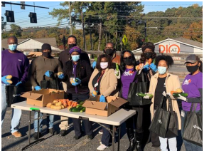 A row of people behind a table of produce.