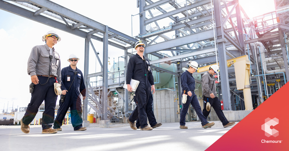 Workers in hardhats walking outside at a plant