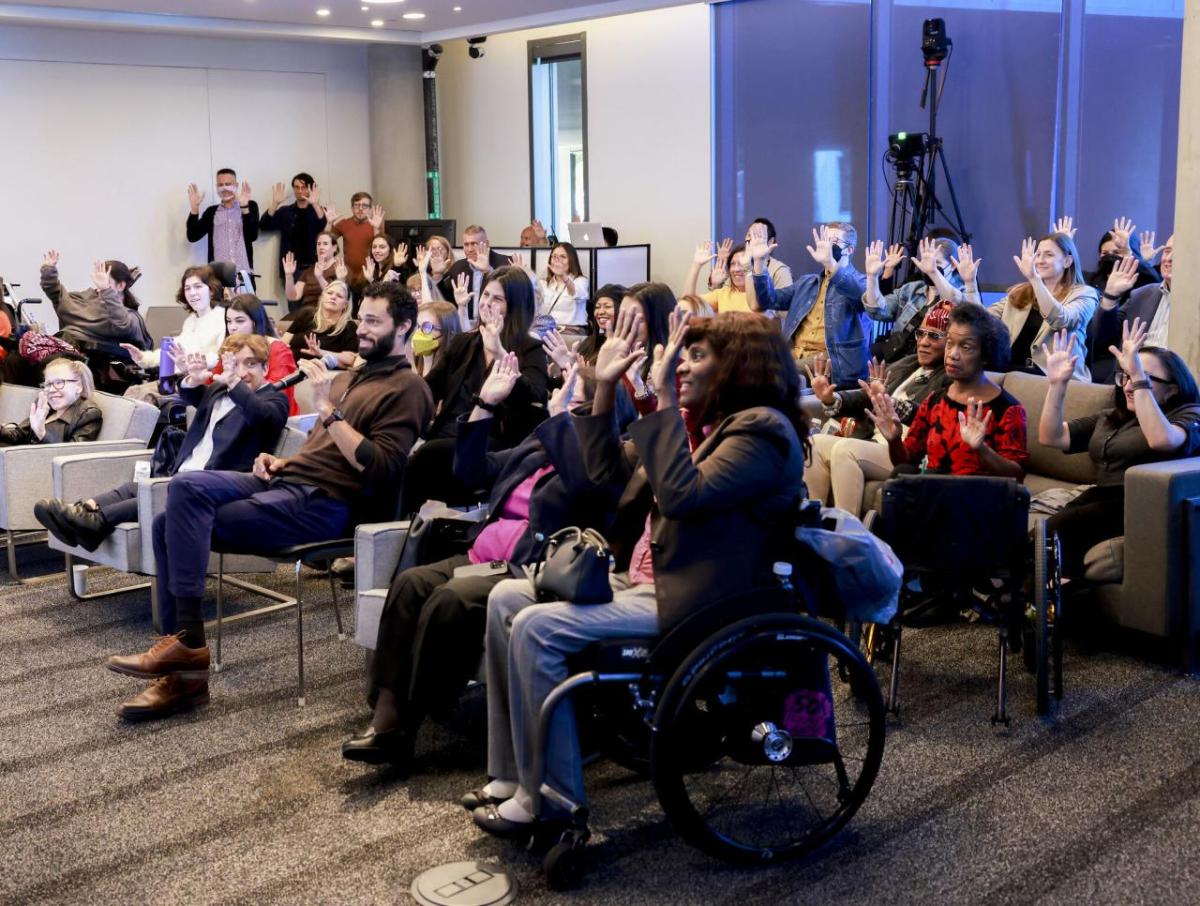 A group of seated people waving both hands.