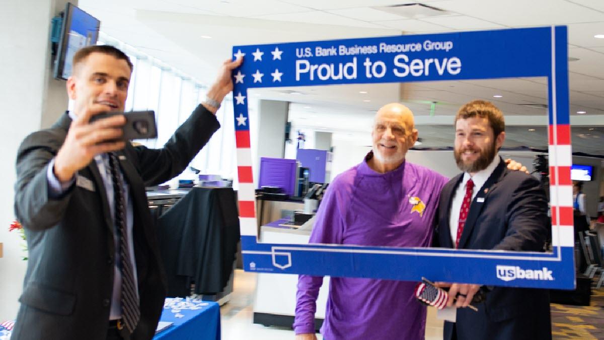 Employee holding up a selfie frame and taking a photo of two people in the frame