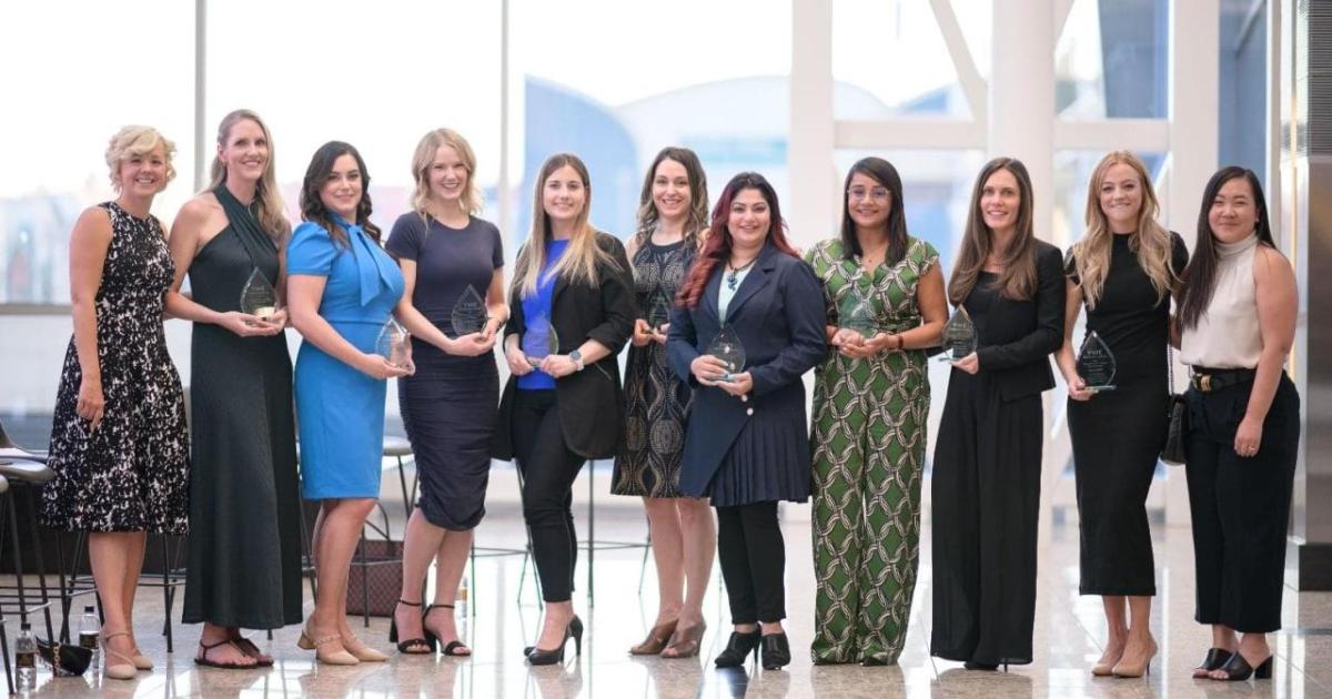 A group of people in a row, each holding an award.