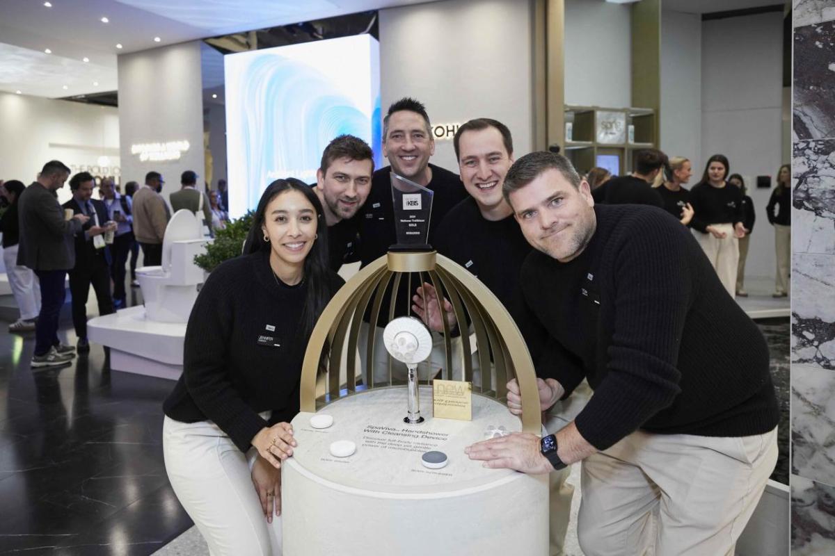 A team of five posed around a display of awards.