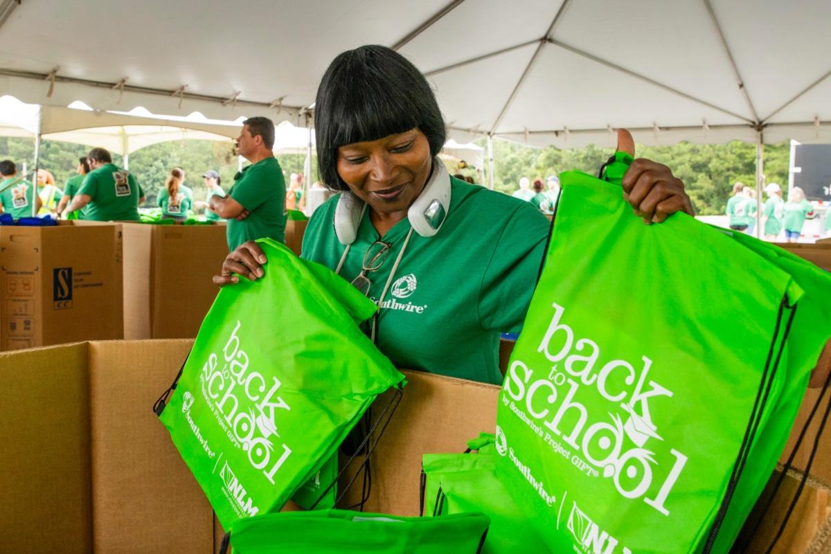 Volunteer holding backpacks of school supplies