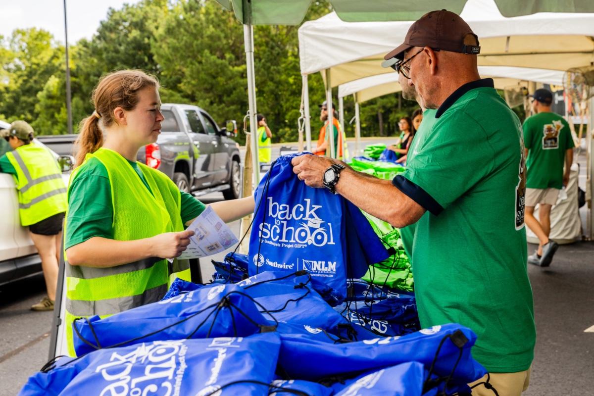 Volunteers organizing backpacks of school supplies