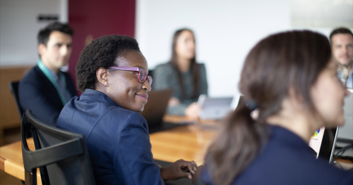 People in business attire gathered around a conference table and smiling