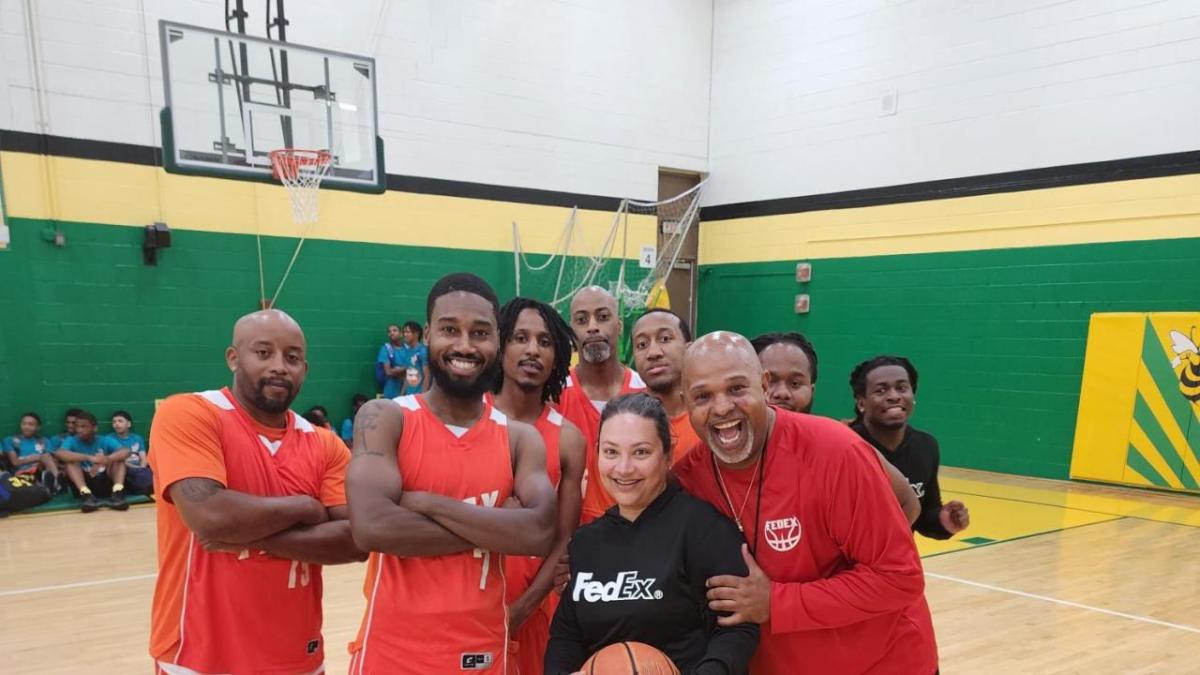 A group of adults and a child holding a basketball in a gymnasium.