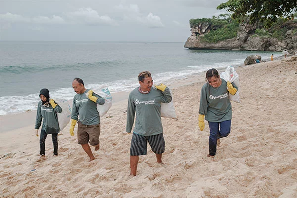 Four volunteers picking up trash on a beach