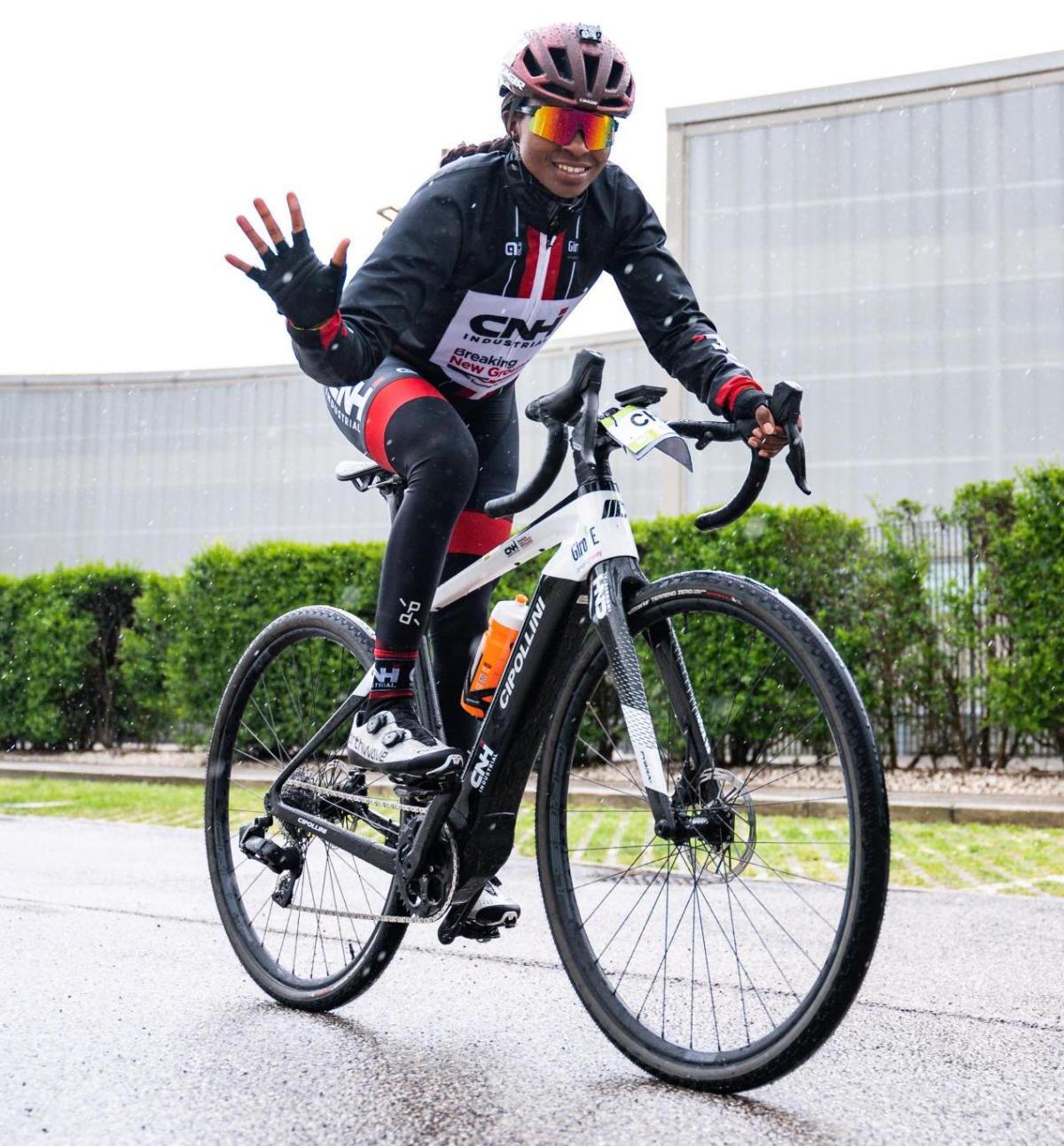 A person riding a bike, waving.