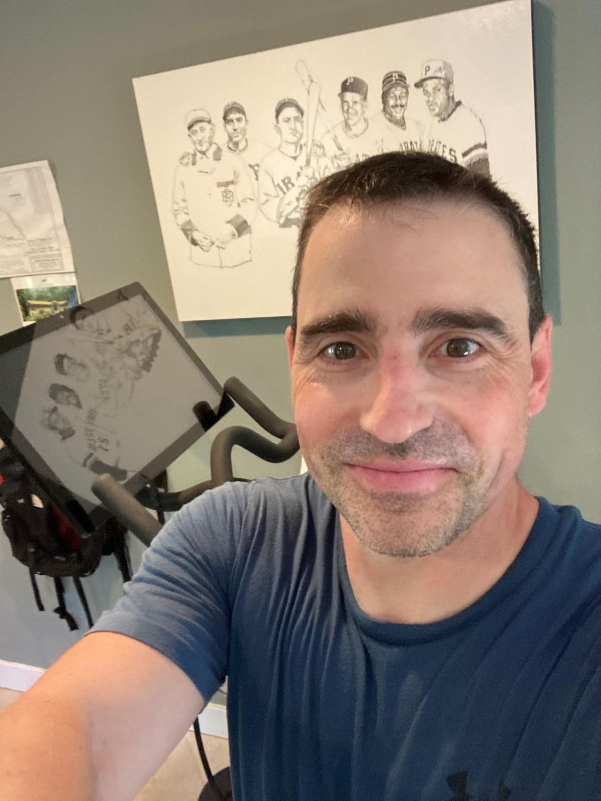 A person smiling next to an indoor bike. 