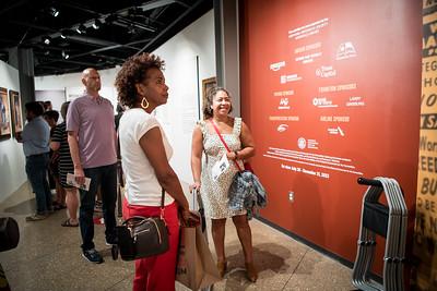 People attending a museum opening, viewing exhibits.