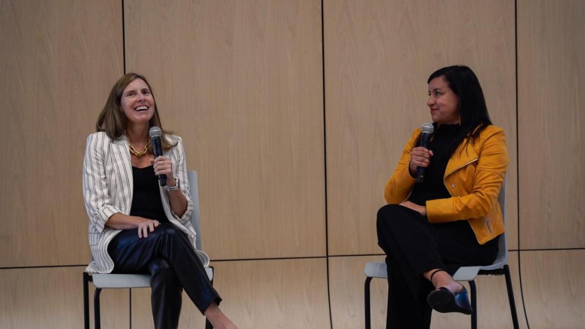 Two seated people speaking with microphones.