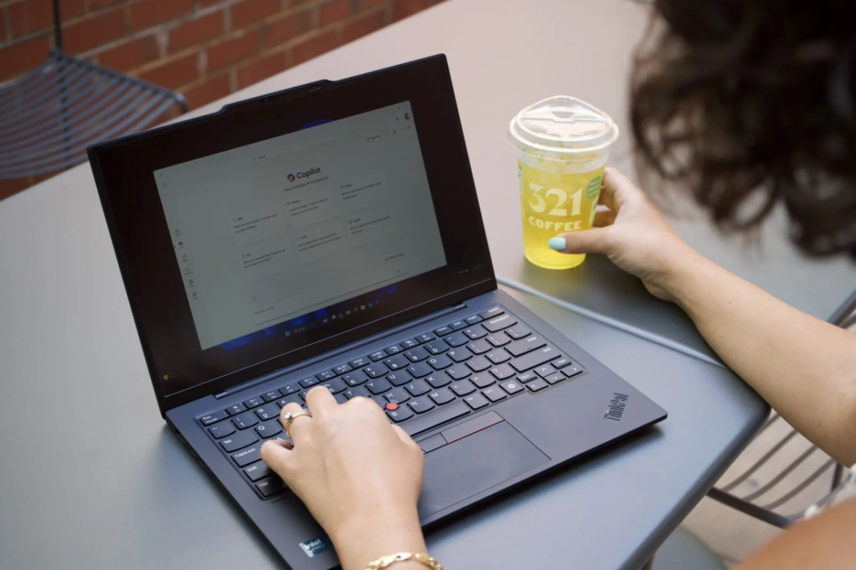 Someone using a laptop while holding a beverage