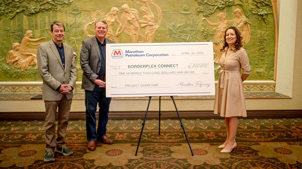 Three people standing next to an oversized check