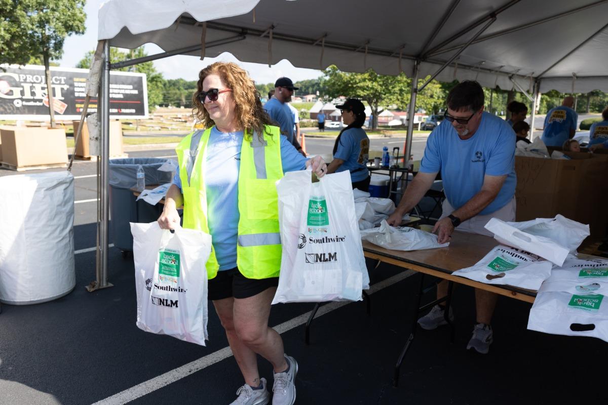 Southwire volunteer holding bags of school supplies