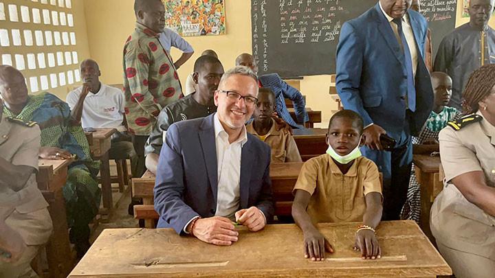 adult sitting next to a child at a school desk in a school room