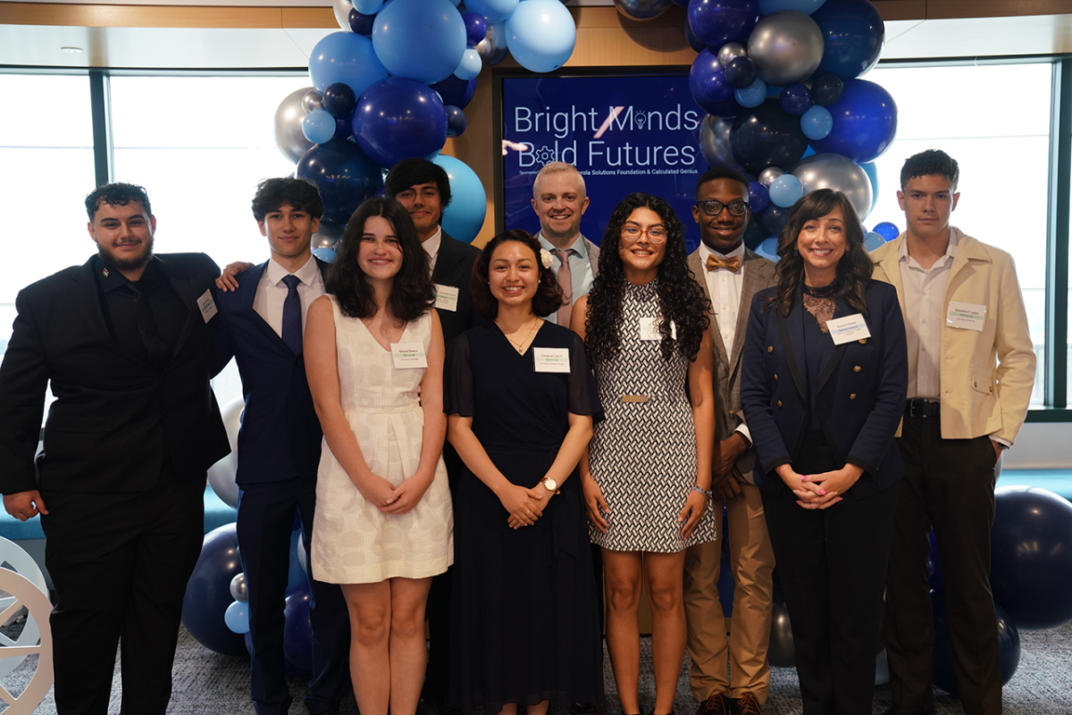 People smiling and standing together under blue balloons