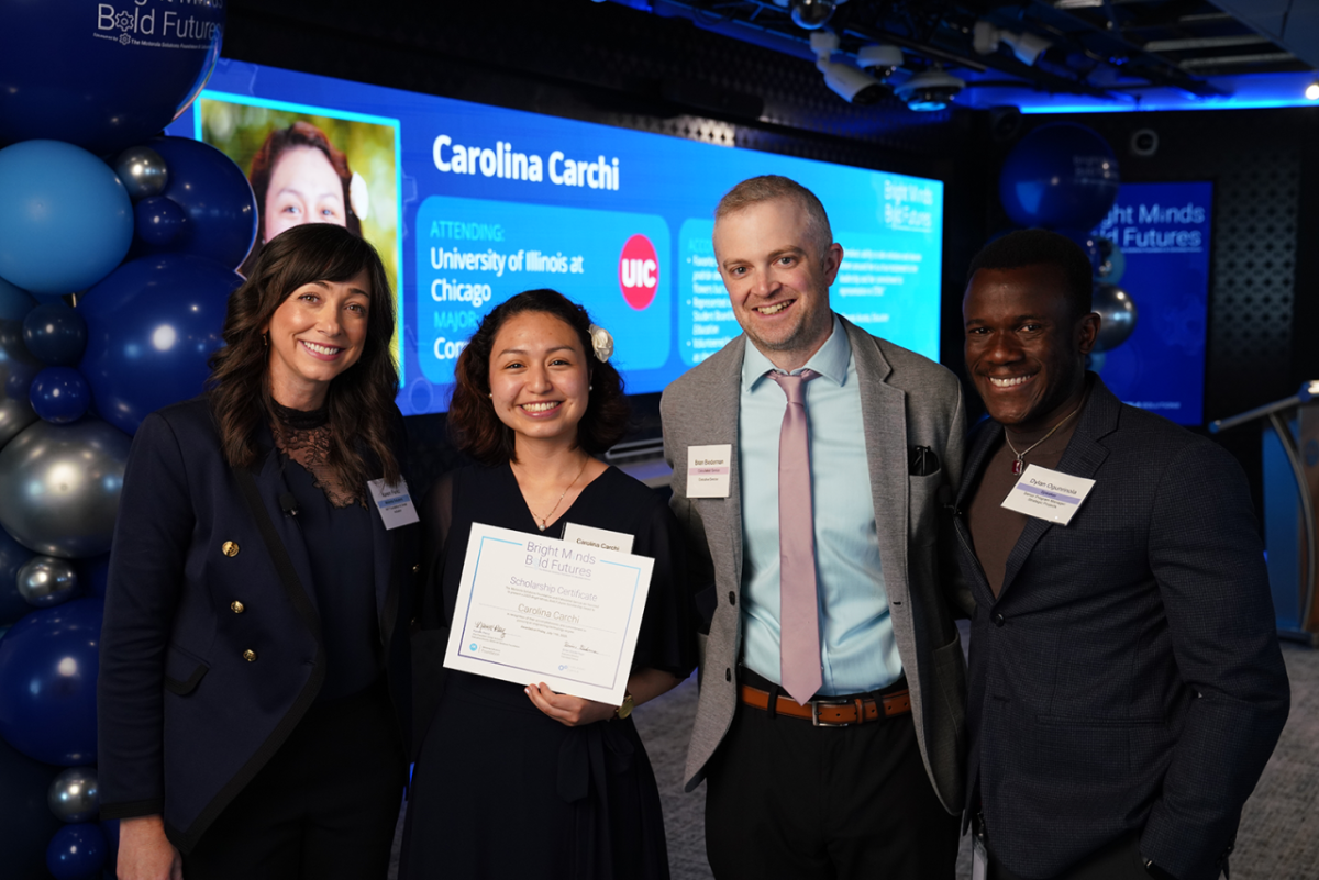 Four people smiling and standing together