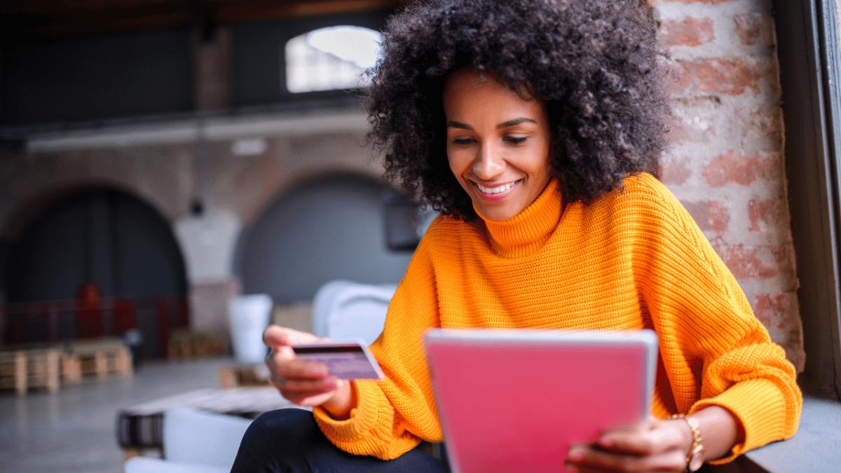 a person holding a credit card in one hand and a tablet in the other