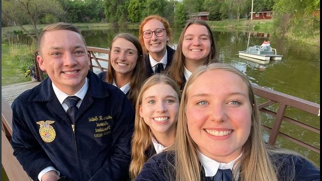 smiling children in navy blue school uniforms standing next to a pond