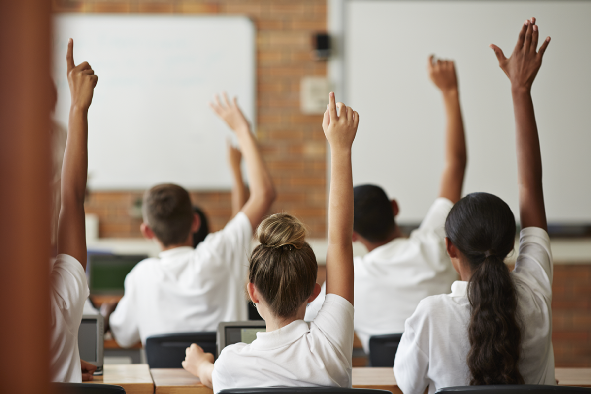 students raising their hands in a classroom
