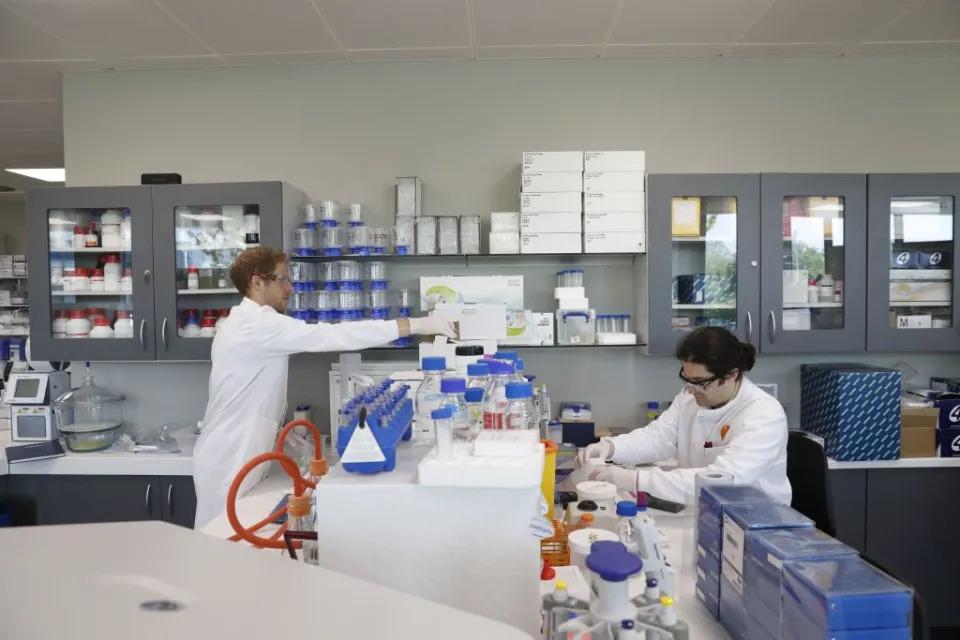 Two people in a laboratory setting wearing protective gear.