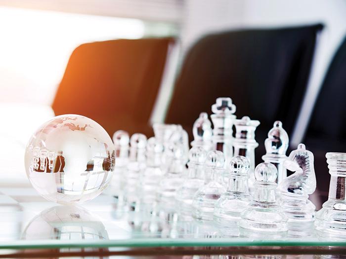 Clear chess set and a small clear globe on a table.