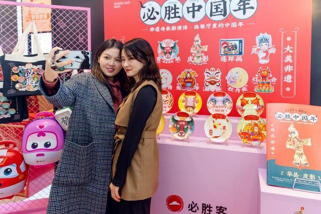 two people take a selfie in front of a display of plates and posters