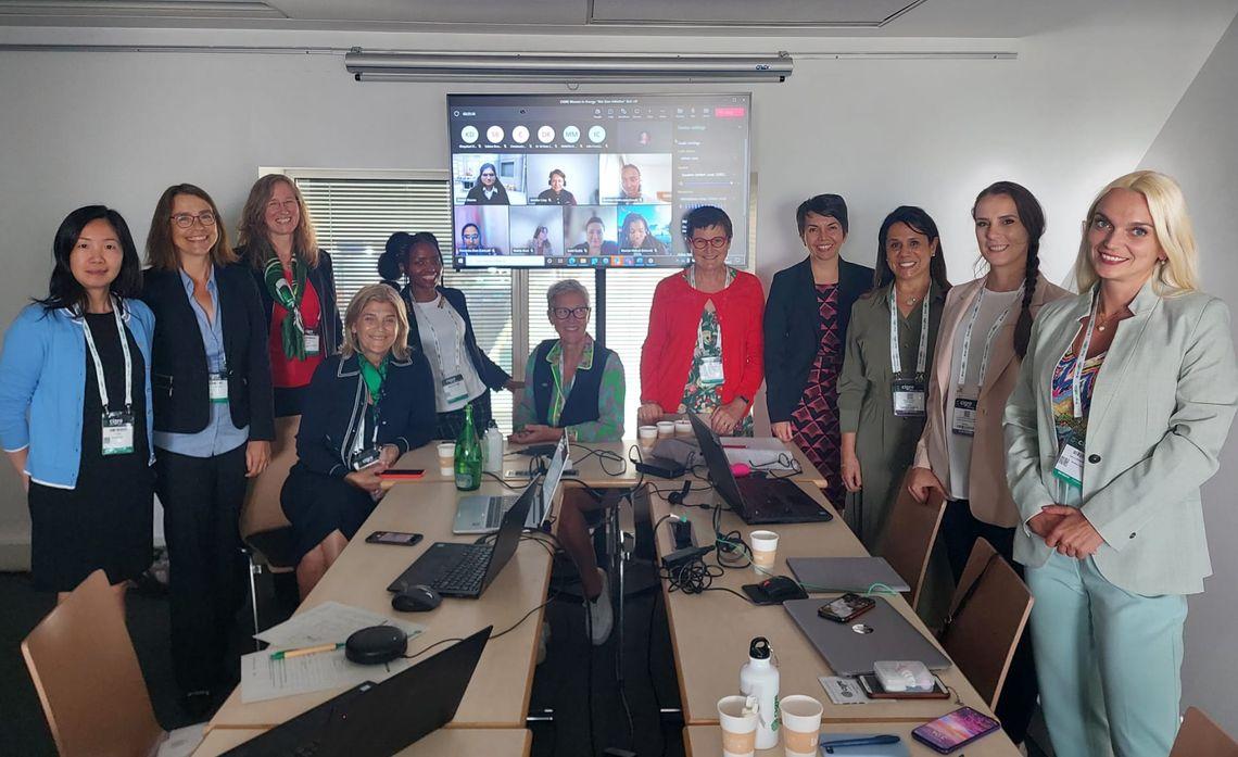 A small team in a conference room, a screen up with virtual participants.