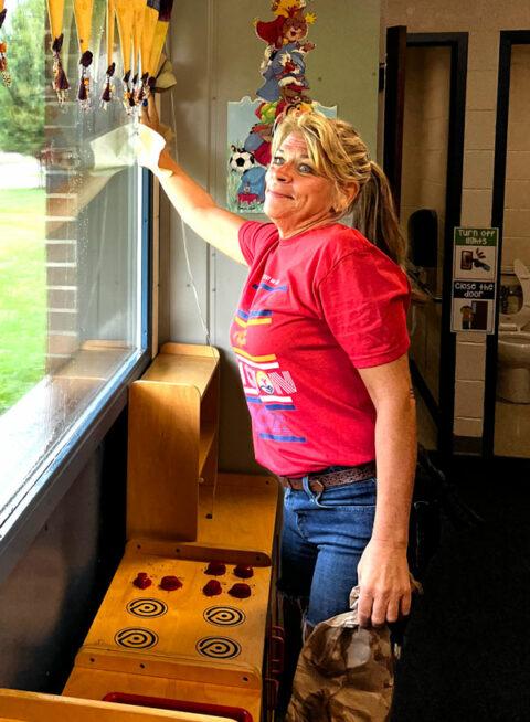 a person cleaning a window in a kids classroom