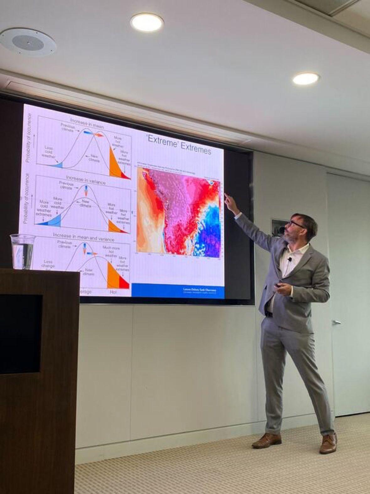 speaker gesturing to a brightly colored climate change graph