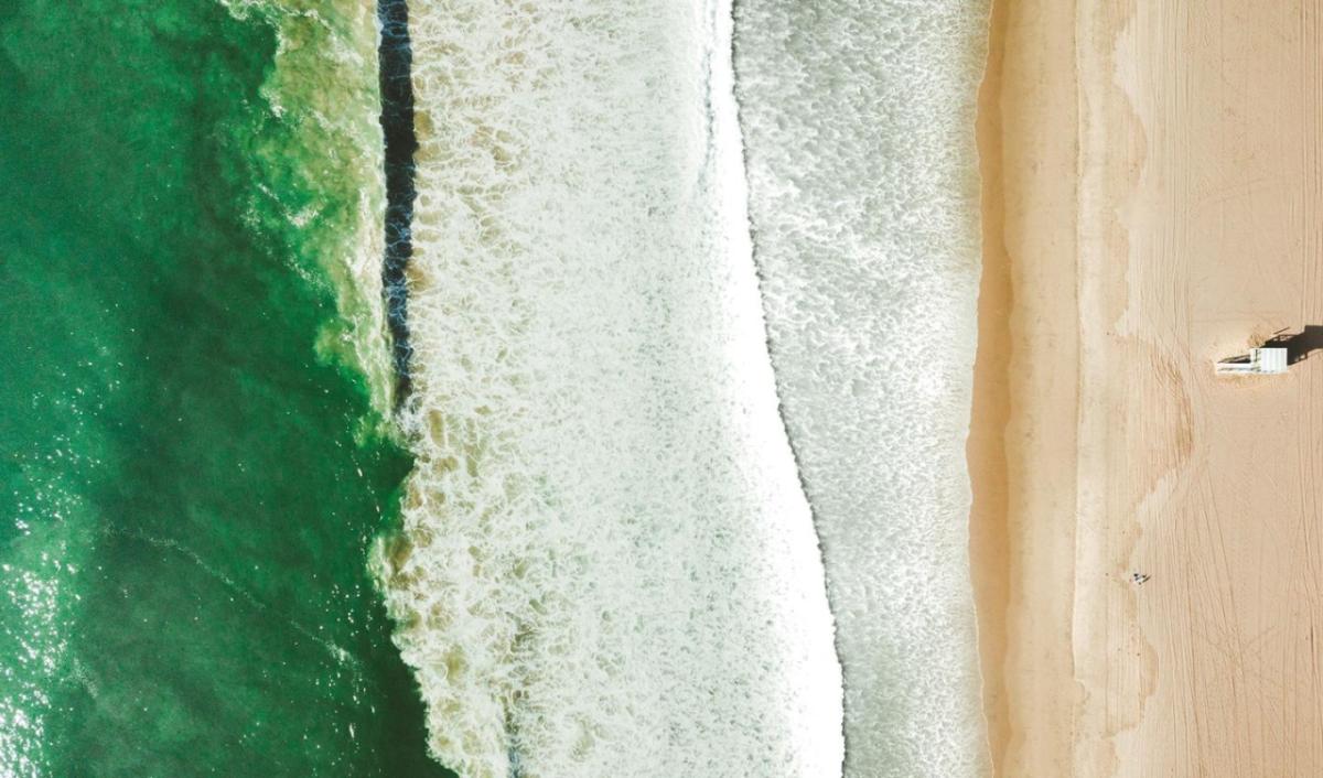 Aerial view of a beach with small waves from greenish water